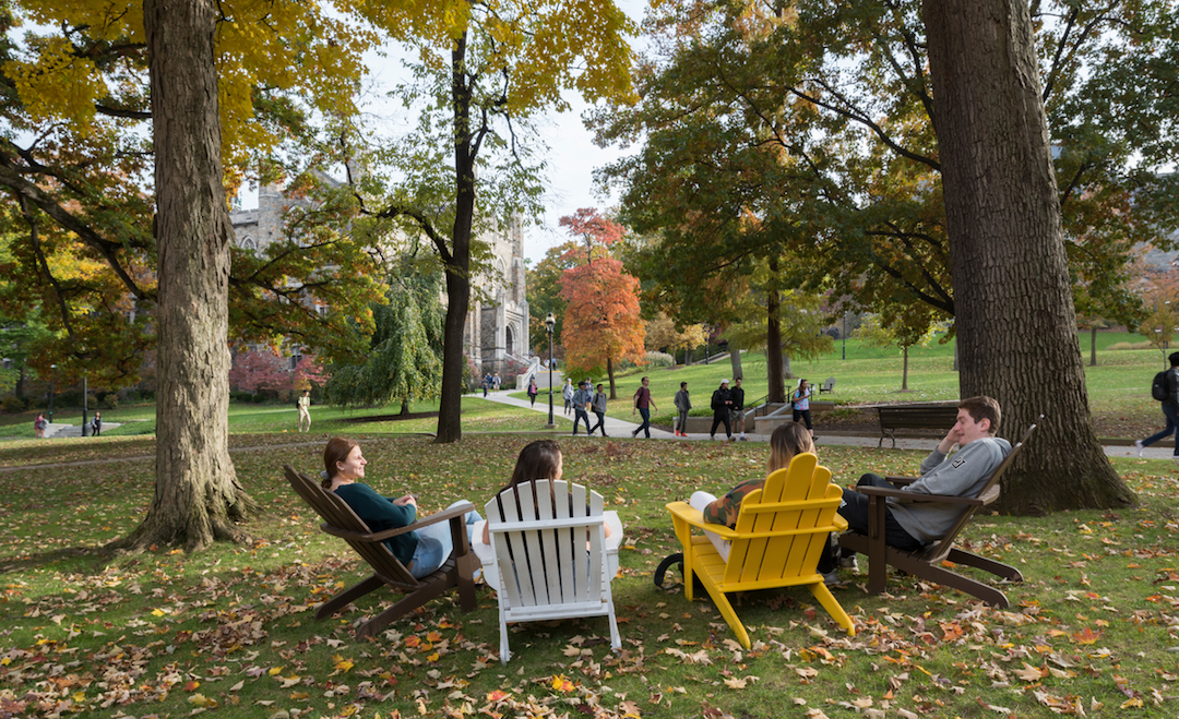 Students sitting in adirondack chairs on campus