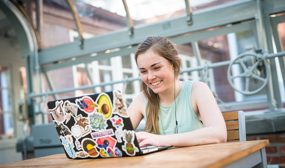 Student smiling at a laptop screen