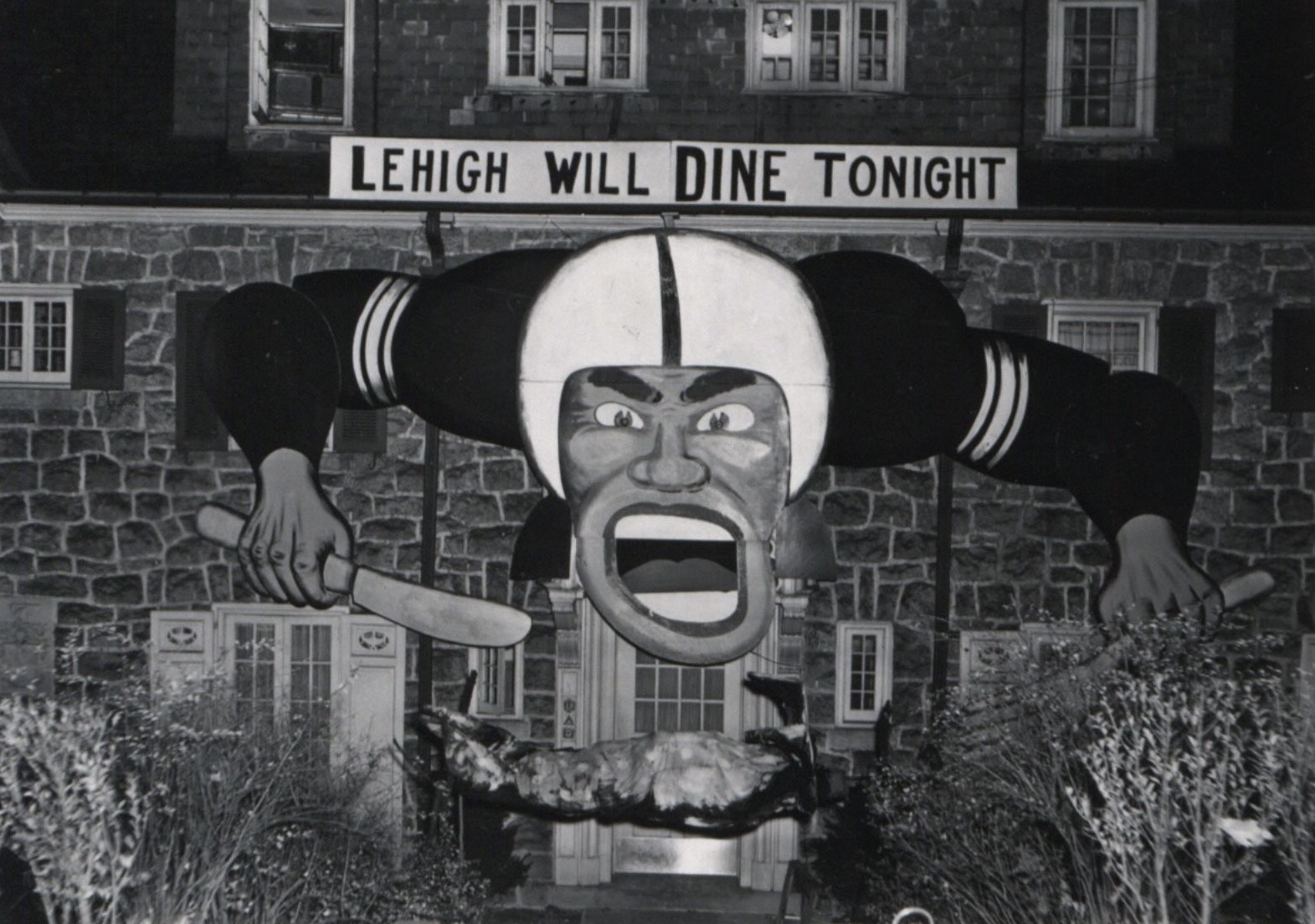 A black-and-white photo shows a banner reading "Lehigh Will Dine Tonight" and a painting of a football player in front of a large stone building. 