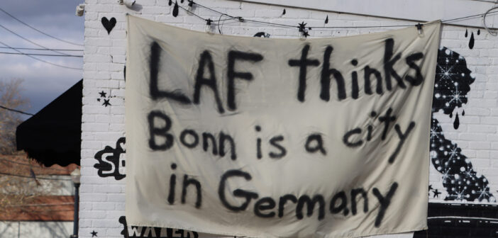 A bedsheet reading "LAF thinks Bonn is a city in Germany" hangs from the front of Bonn Place Brewing Company. 