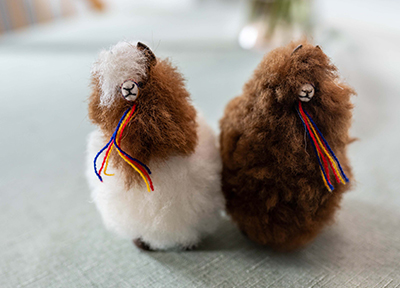 Two stuffed toy alpacas, one white and one brown